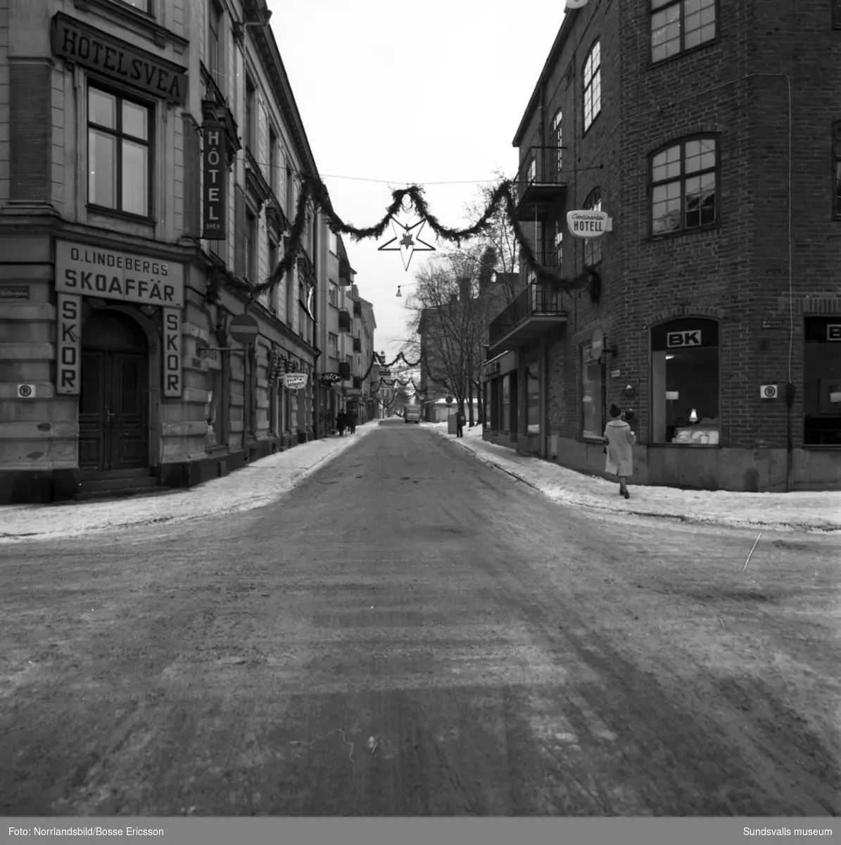 Nybrogatan i Sundsvall med bland annat frukthandlare Berg och olika butiker och hotell utmed gatan. Fotograferat för Nybrogatans Allehanda.
