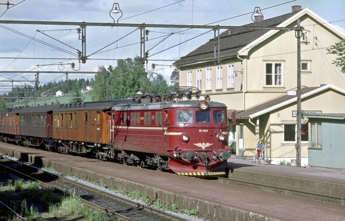 Persontog Oslo V - Spikkestad med elektrisk lokomotiv El 13 2141 kjører inn på Røyken stasjon. Mens de fleste togene var motorvognsett som pendlet mellom Asker og Spikkestad ble det kjørt noen rushtidstog hele veien til/fra Oslo V.