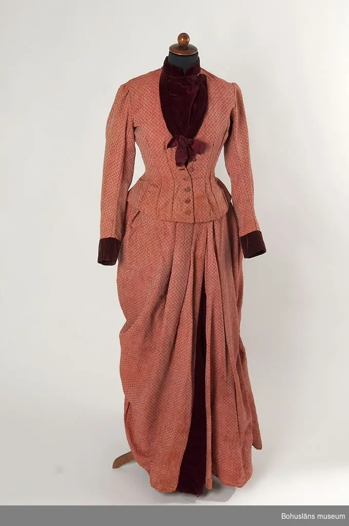 Enligt uppgifter vid studiebesök från textilintendent Berit Eldvik, Nordiska museet, är mönstret sannolikt hämtat ur någon av de tiotal  handböcker i mönstervävning som publicerades mellan åren 1826 - 1843 av vävarfamiljen Ekenmark från Östergötland. 
Observera att mönstret i klänningens turnyr eller släp är ett snarlikt men dock annat än klänningens övriga mönster.