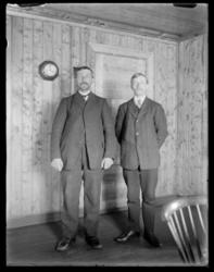 To menn i helfigur fotografert inne i et rom