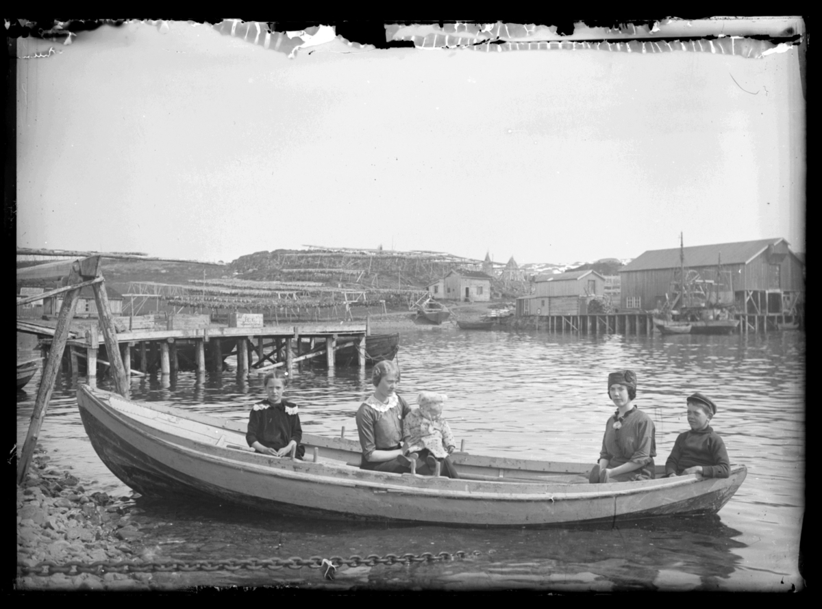 Gruppebilde tatt ombord i en robåt; ombord er det to kvinner og tre barn