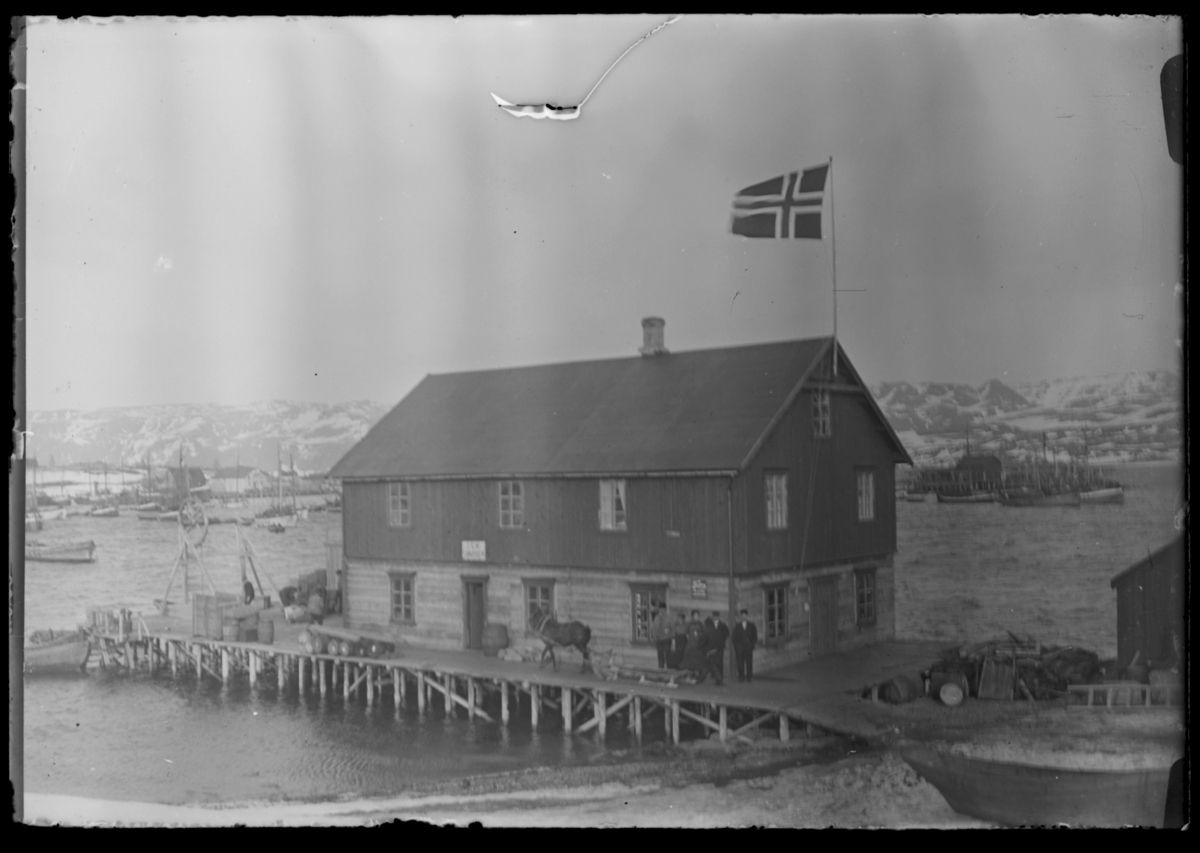 Et hus ute på kaia i Båtsfjord. Flagget er heist til topps