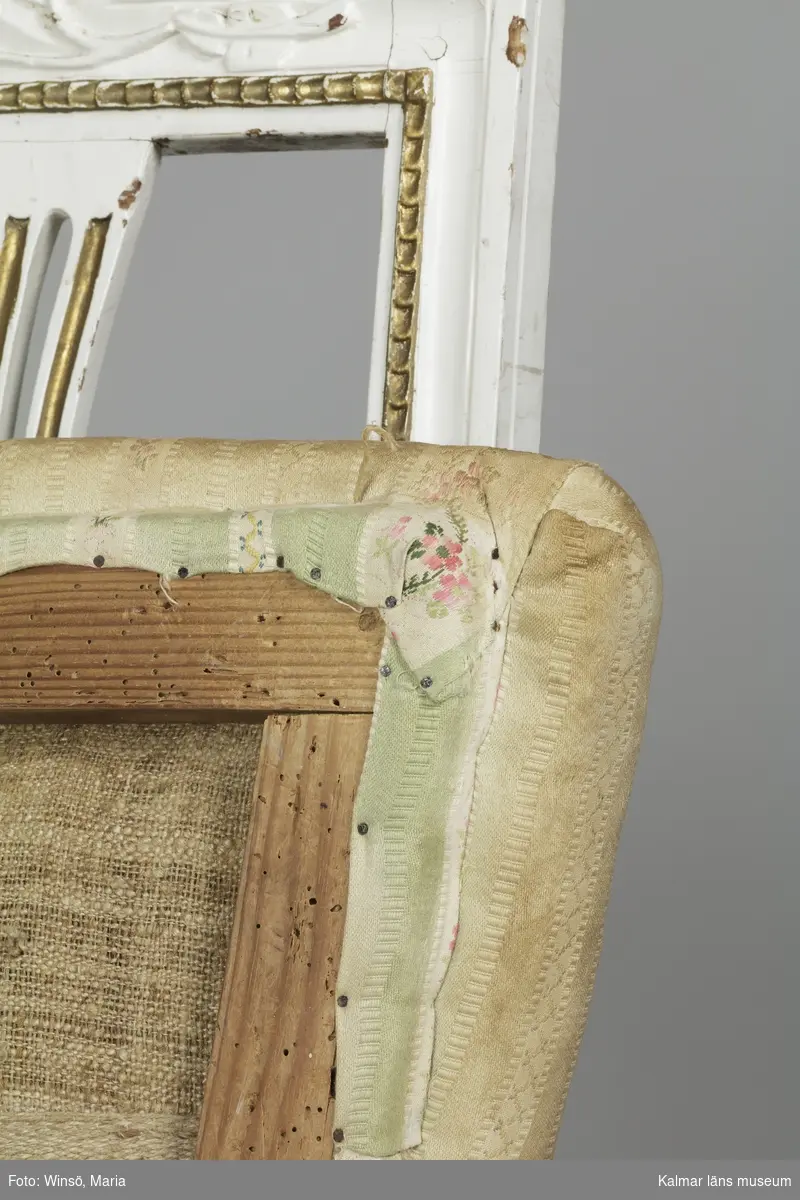 KLM 12727:2. Stol, ryggbrickstol av trä. 8 st. Två något olika grupper av stolar med fyra av varje, den ena gruppen med förgyllda detaljer och den andra helt vitmålad. I övrigt likadan dekor. Den ena gruppen stolar (stol 1-4) är vitmålade med guldfärgad äggstavsdekor på fram- och sidosargarna. Dekor på ryggöverstycke samt framsarg i form av humlekvistar. Benen är kannelerade, delvis förgyllda och nedåtavsmalnande. Ryggbrickan är genombruten och har en form av ett kopplat spjälknippe. Sitsen är stoppad och klädd med textil med ränder med blomsterslingor. Textilen är mycket blekt och originalfärgen syns på några ställen, då i grönt. Gruppen med stolar som är utan förgyllning (stol 5-8) har tidigare haft sitsarna klädda med rosa textil med mönster av lagerkransar med urna i mitten. Likadan textil kan ses på dyna i soffan KLM 27787. Gustaviansk.