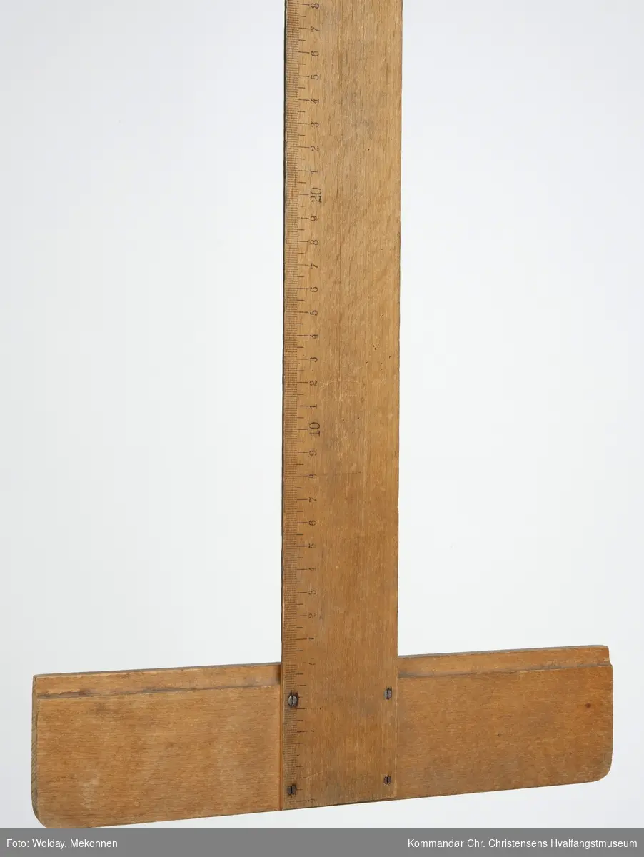 Form: T-form, lang linjal med cm-skala. Rundt hull i enden