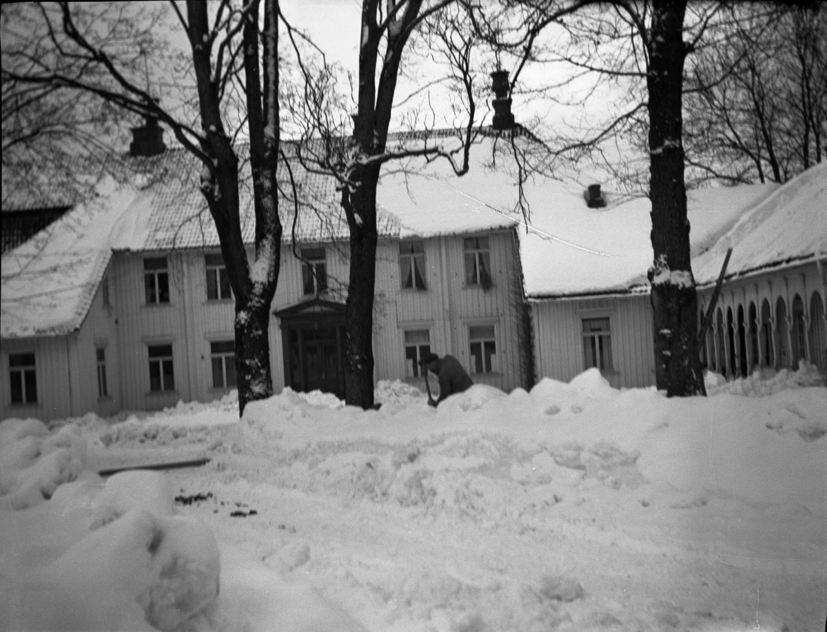 Fotoarkivet etter Gunnar Knudsen. En mann som måker snø foran Borgestad gård.