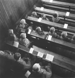 Inne i Karesuando kirke. Folk sitter på benkene. Dette er an