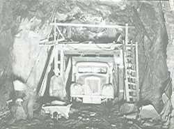 Vannkraftutbygging, lastebil og arbeidar i tunnelåpningen.