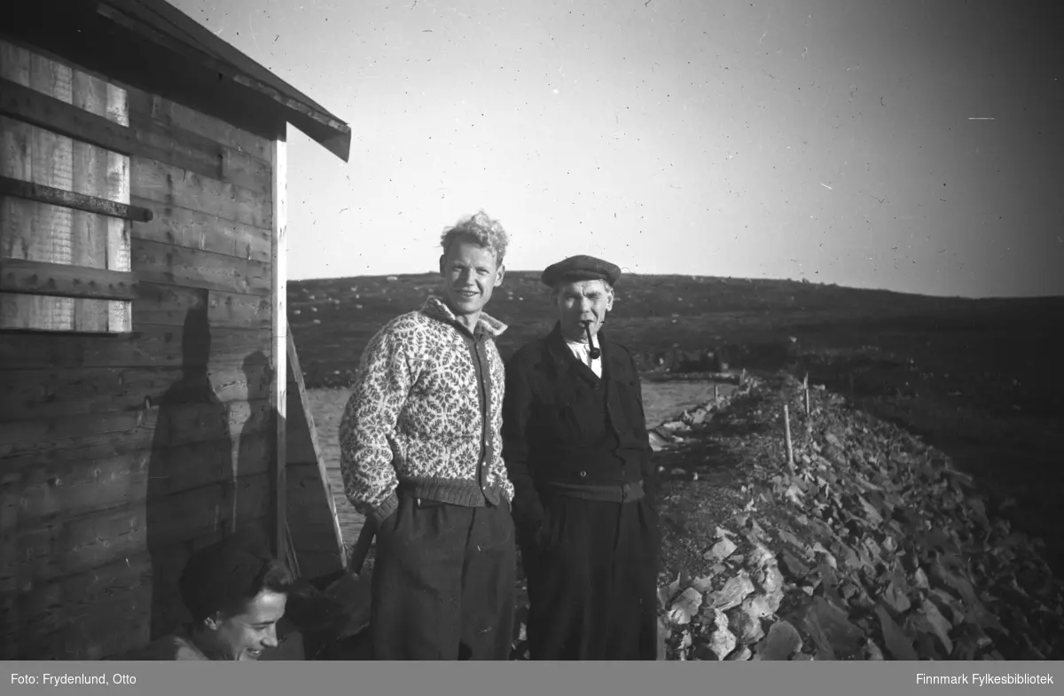 Ved Byvannet i Vadsø rett etter annen verdenskrig. Fra venstre: Ukjent, Oluf Østbø ukjent. De står ved ei hytte, i bakgrunnen demninga som samlet drikkevannet i å renne unna