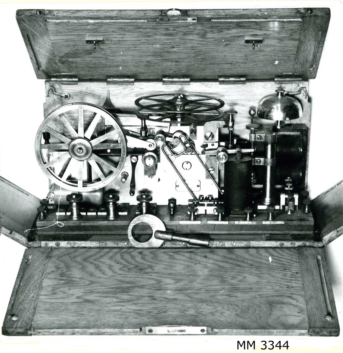 Telegrafapparat av metall, förvarad i låda av trä.