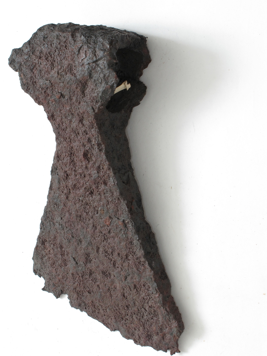 Øks av jern, nærmest som Jan Petersen: Vikingesverd,fig. 43 - L-typen - men med sterkere svunget overkant og kortere underkant. Forrustet. 3 av skaftflikene mangelfullt bevart. 