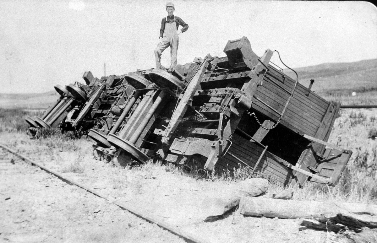 Amerikabilder, Per Mæhlum, Vallset.
En tom godsvogn, jernbanevogn er veltet av stormen. Mannen som står oppå den veltede jernbanevogna heter Salthammer. Katheryn, Nord-Dakota, USA. 20. juli 1911.