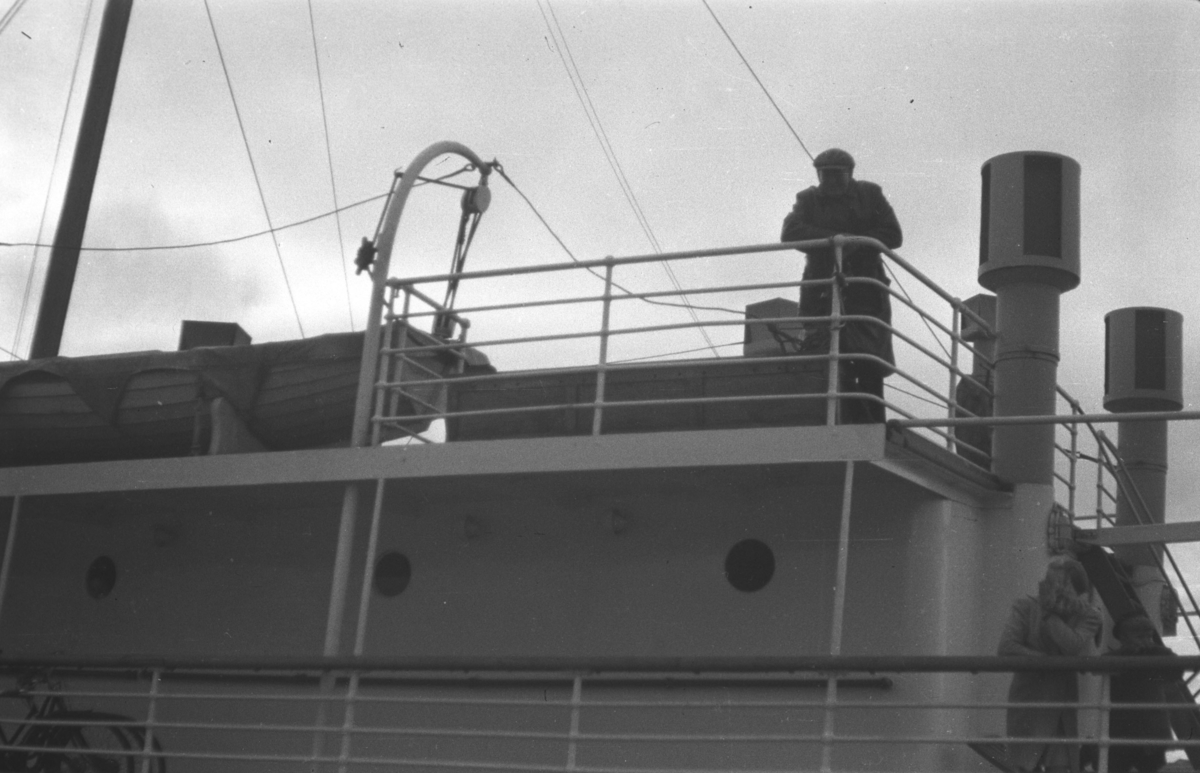 To ukjente personer fotografert på dekket av en stor båt. Stedet der båten ligger er ukjent.