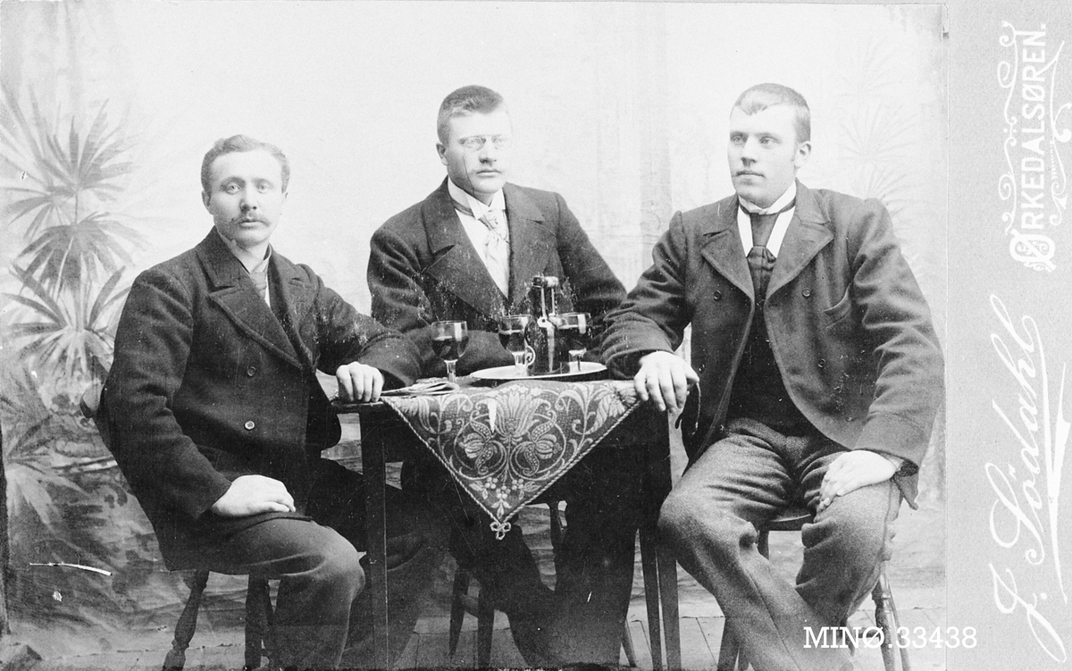 Tre menn rundt et bord med godt drikke