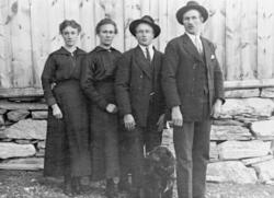 To menn og to kvinner med hund utenfor et hus på Sæther.