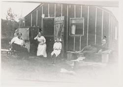 Fire personer foran et uferdig hus. I Amerika?