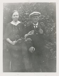 Ungt par i fine draktklær. Kvinnen med en kvist av en busk i