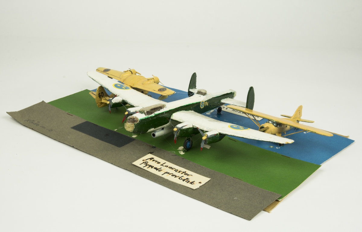 Tre flygplansmodeller monterade i kartong märkt "16".
Tp 81 Grumman Goose, Tp 79 Norseman, Avro Lancaster "flygande provbänk".