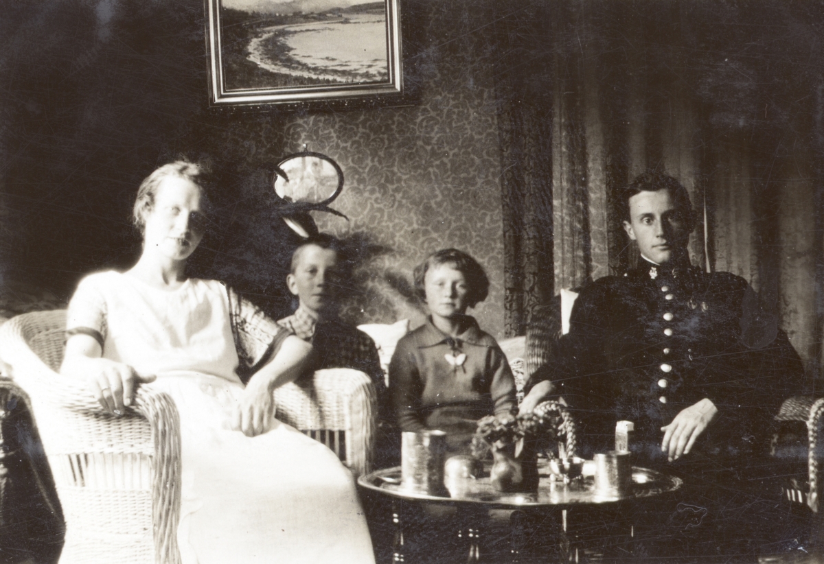 Kvinne, to barn og mann i uniform ved et røykebord.