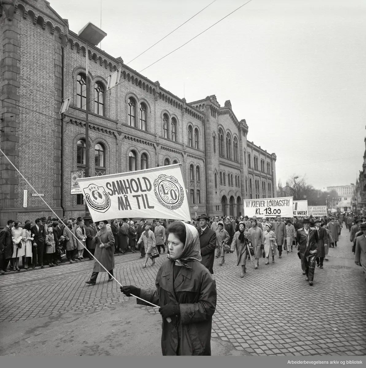 1. mai 1963 i Oslo.Demonstrasjonstoget i Karl Johans gate..Parole: NHKF Samhold må til LO.Parole: Vi krever lørdagsfri kl. 13.00