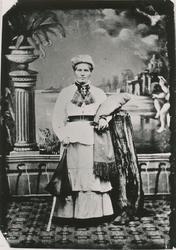 Portrett av en kvinne med finklær hos fotografen.