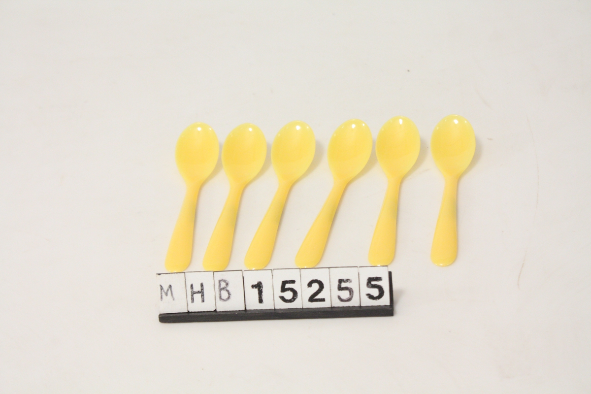 Campingkoffert med servise i gul og hvit plast for seks personer: 6 gule suppeboller, 6 hvite tallerkener, 6 gule kaffekopper, 6 gule drikkeglass, 6 lyseblå holdere for egg, 6 gule plastskjeer for egg, 6 metallteskjeer, 6 metall spiseskjeer, 6 kniver i metall og 6 gafler i metall. I tillegg er det en flaskekork-opptrekker i metall, en bokseåpner, en gul plast salt- og pepperbørse, og et etui med kortstokk. I tillegg er en papirpose med sukker og en plastboks med salt. Alt er ordnet i rom der noe er pakket ned i to gjennomsiktige plastesker. Eget rom for koppene. Suppeboller og bestikk er festet med lærstropper i koffertlokkets innside.