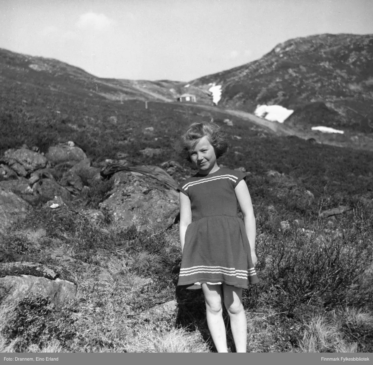 Turid Lillian Drannem (Karikoski) fotografert i fjellet, i bakgrunnen ser man en liten hytta og noen små snøflekker