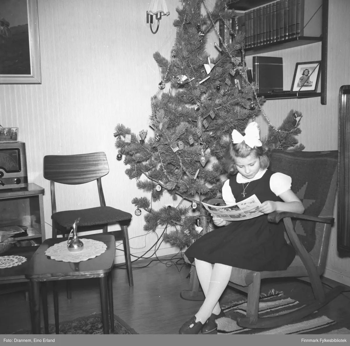 Turid Lillian sitter i gyngestolen og leser ved juletre