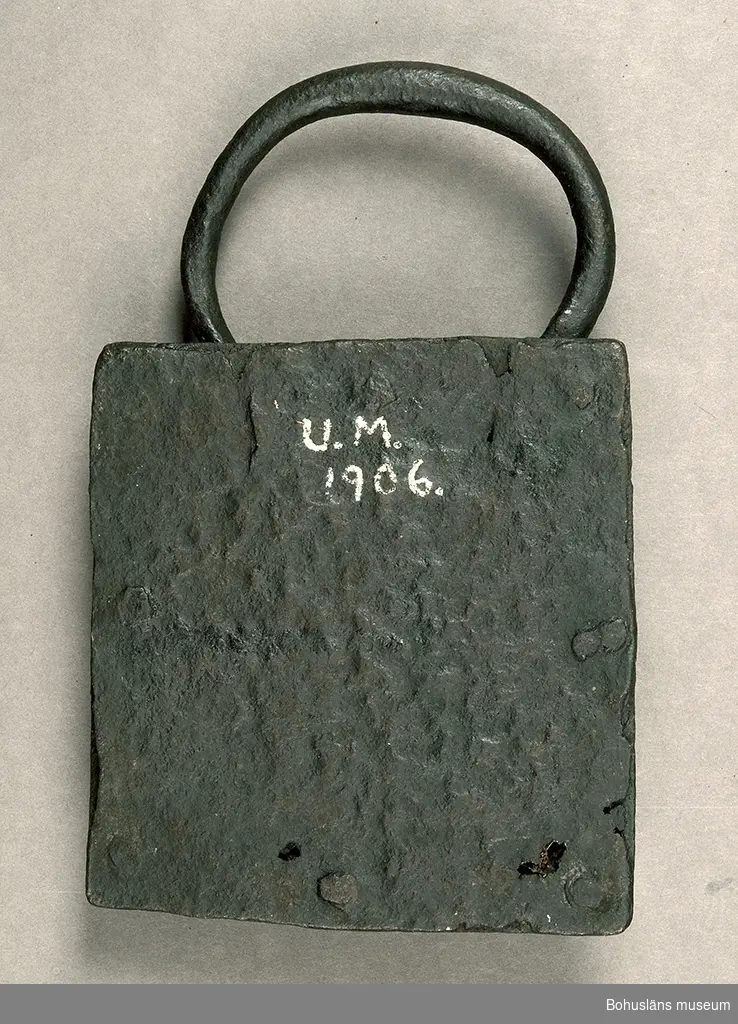 Ur handskrivna katalogen 1957-1958:
Järnlås
L. c:a 14,8 cm. Br. c:a 13,5 cm.
Hänglås av ålderdomlig typ. 
Handtagets Br.c:a 10,5 cm.
Låset ngt. defekt. Nyckel saknas. 

Lappkatalog:  87