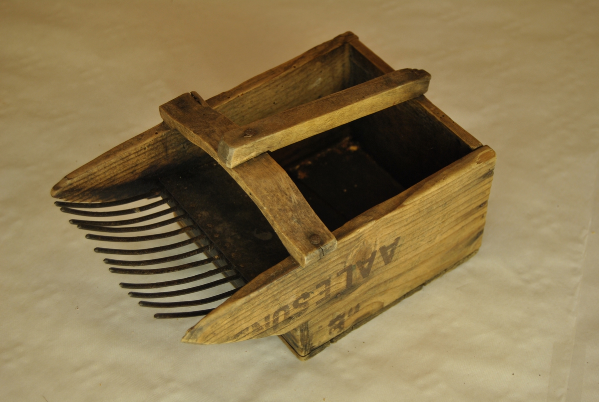 Bærplukker i tre med jerntenner. Med håndtak. Lagd av margarinkasse fra Aalesund.