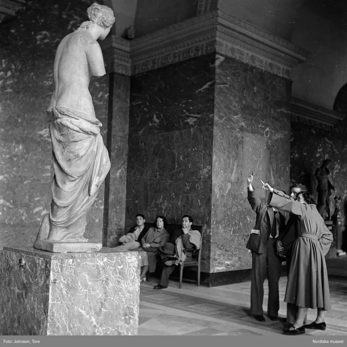 Paris. Museibesökare betraktar en antik staty.