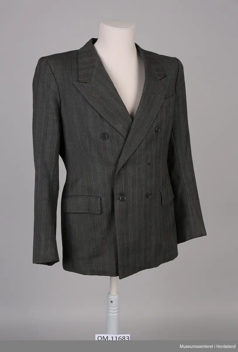 Form: rett jakke med lange slag, dobbeltknappa, ei brystlomme og to lommer, ei på kvar side i livet
