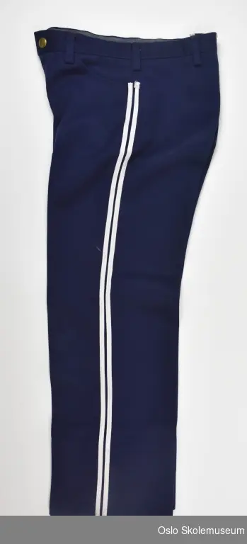 Marineblå bukse fra Lambertseter skoles musikkorps til barn. Buksen har to hvite striper langs siden av hvert bein. knapp og glidelås i metall.