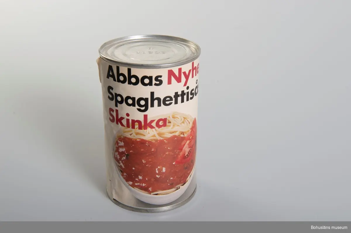Cylindrisk burk med dekortryckt pappersetikett: Bild av spagetti
med sås och text i svart och rött: "Abbas Nyhet. Spagettisås. Skinka.
Dessutom tillagningsinformation och innehållsdeklaration samt prismärkningskod

Om givaren: Se UM26667