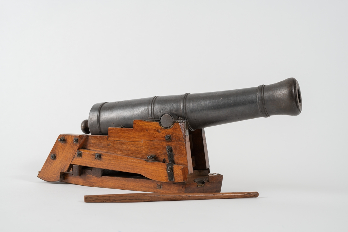 Kanonmodell: styckelåda, modell av trä, beslagen, med kanon av järn, 24-pundig, kapten Malmstens modell. Tillbehör: 1 st brok.