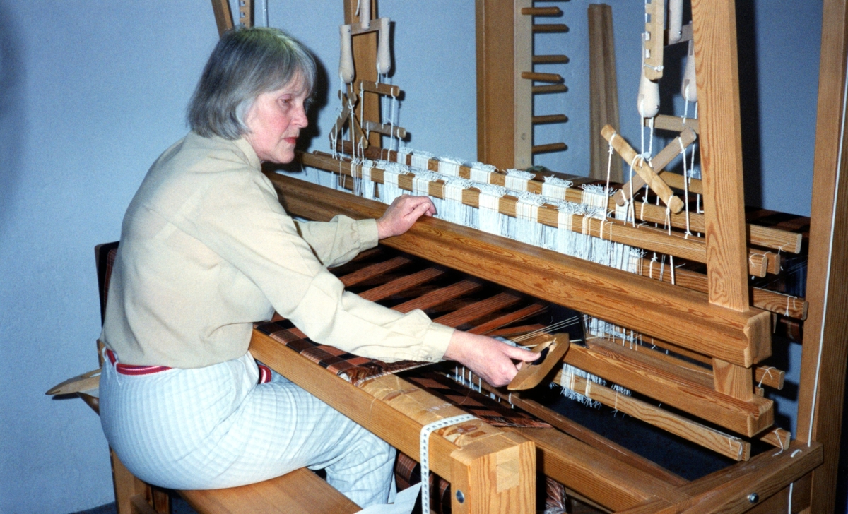Emy Johansson arbetar hemma i sitt kök med väven till Kållereds Hembygdsdräkts sjal, Torrekulla 1980-tal. Relaterade motiv: Relaterade motiv: A2911-A2917.