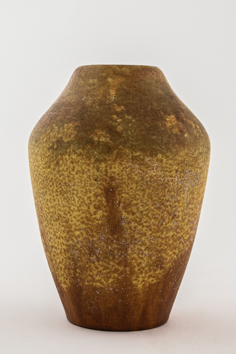 Pæreformet vase av leirgods. Overflaten er dekket av en matt gul- og oransjefarget glasur, tidvis spettet.