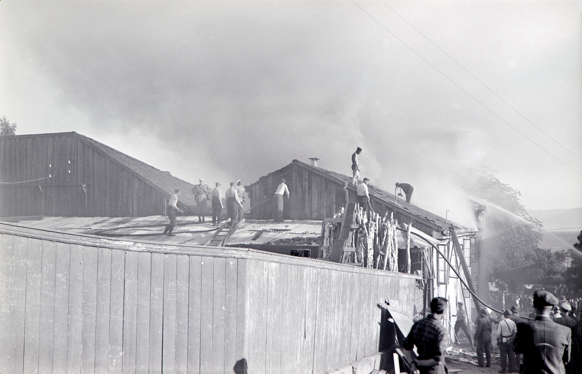 Brann i Lierbakken, Torggata 65, søndag den 25. Juli 1943. Lokalene huset Folkebiblioteket i Hamar, Politiet, Kemner kontoret og Det komunale Reviskons kontoret. Mye folk, slukkningsarbeid. Bildet er tatt fra Grønnegata.