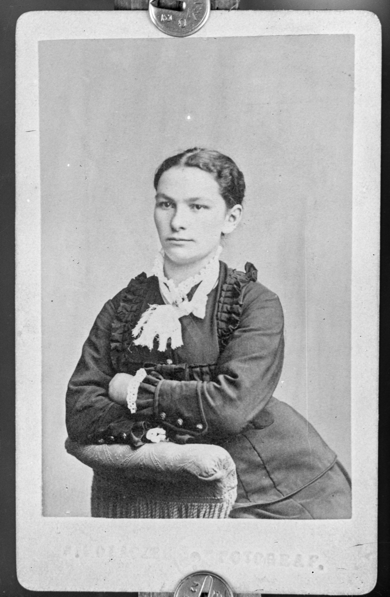 Reprofotografi. Portrett av en ung kvinne med rysjer på kjolen som sitter i en stol.