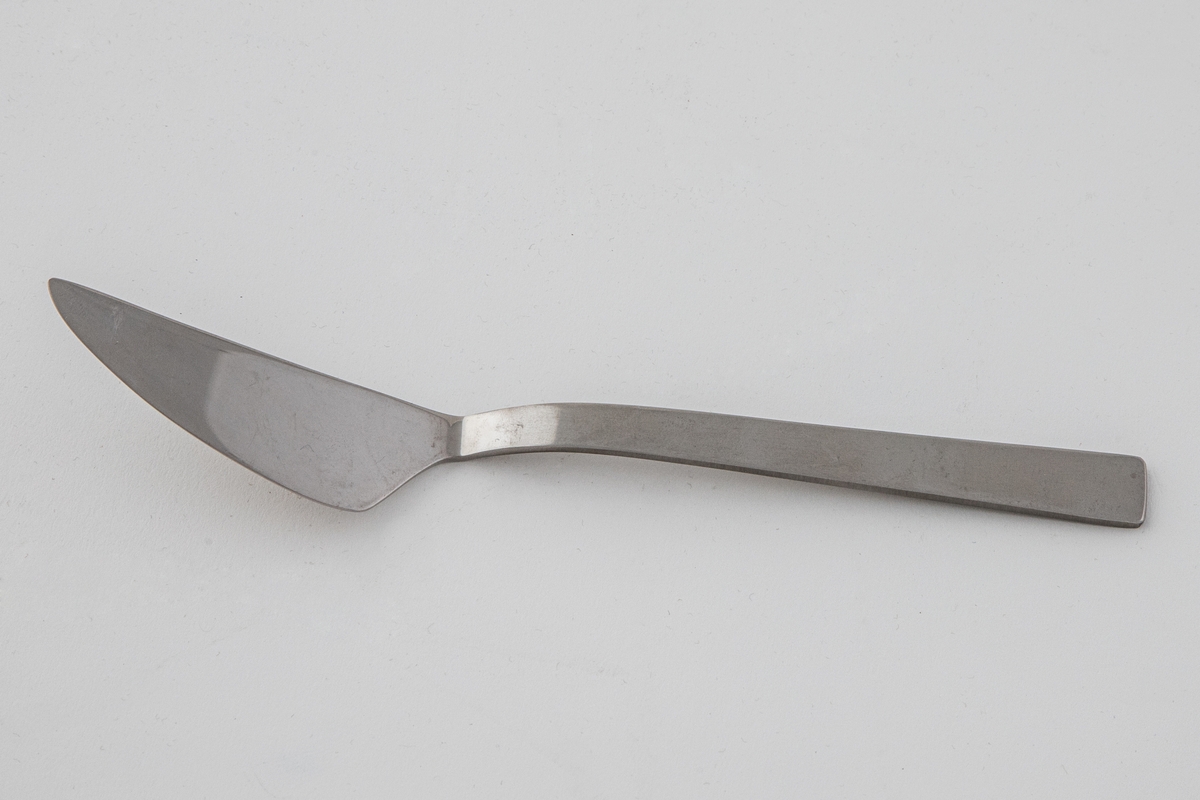 Liten serveringskniv i polert, rustfritt stål. Bladet danner en butt vinkel fra det rettlinjede skaftet. Sistnevnte er mattert, mens bladet er polert, slik at det oppstår en kontrast mellom de blanke og matte partiene.