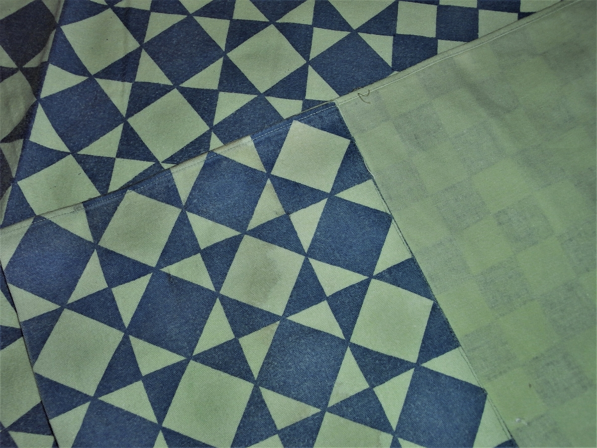 Rent geometrisk konstruert stofftrykk i metervare. Består av vekselsvis eplegrønne og mørk blågrønne, diagonale striper. Hver stripe bestående av kvadratruter, vekselsvis ensfargede og tofargede. De tofargede fremkommer ved en innvendig oppdeling i rettvinkledde trekanter. Rapporten har også større felt i rene sjakkruter.
