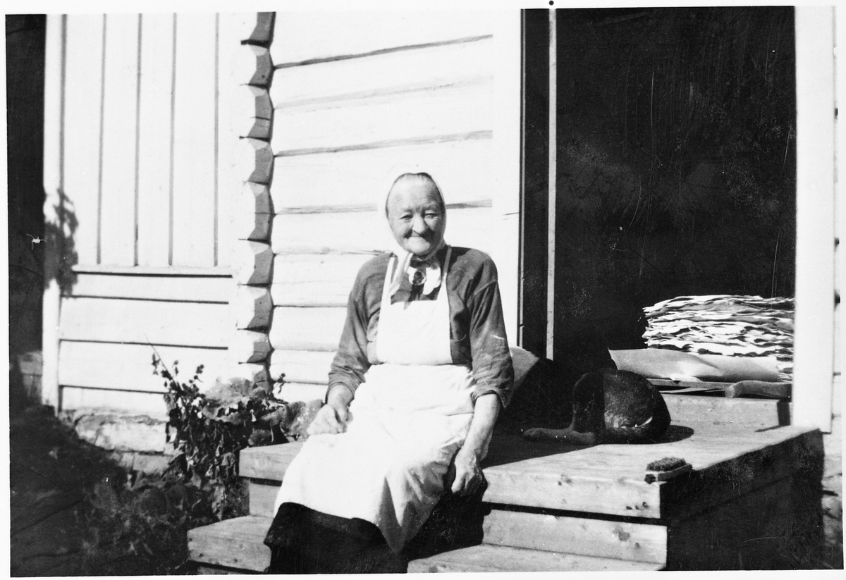 Bakstekjerringa Berthe Enge med en del av dagens produksjon. Hun har bakt "Hårdagsbrød" (kornbrød). Bildet er tatt på Gården Lie i Østre Toten ca. 1935.
