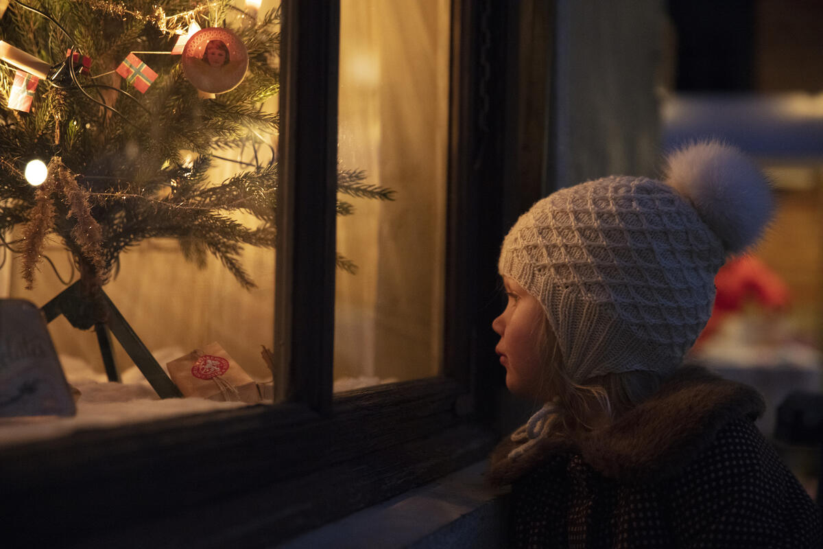 En jente titter inn i et julepyntet butikkvindu (Foto/Photo)