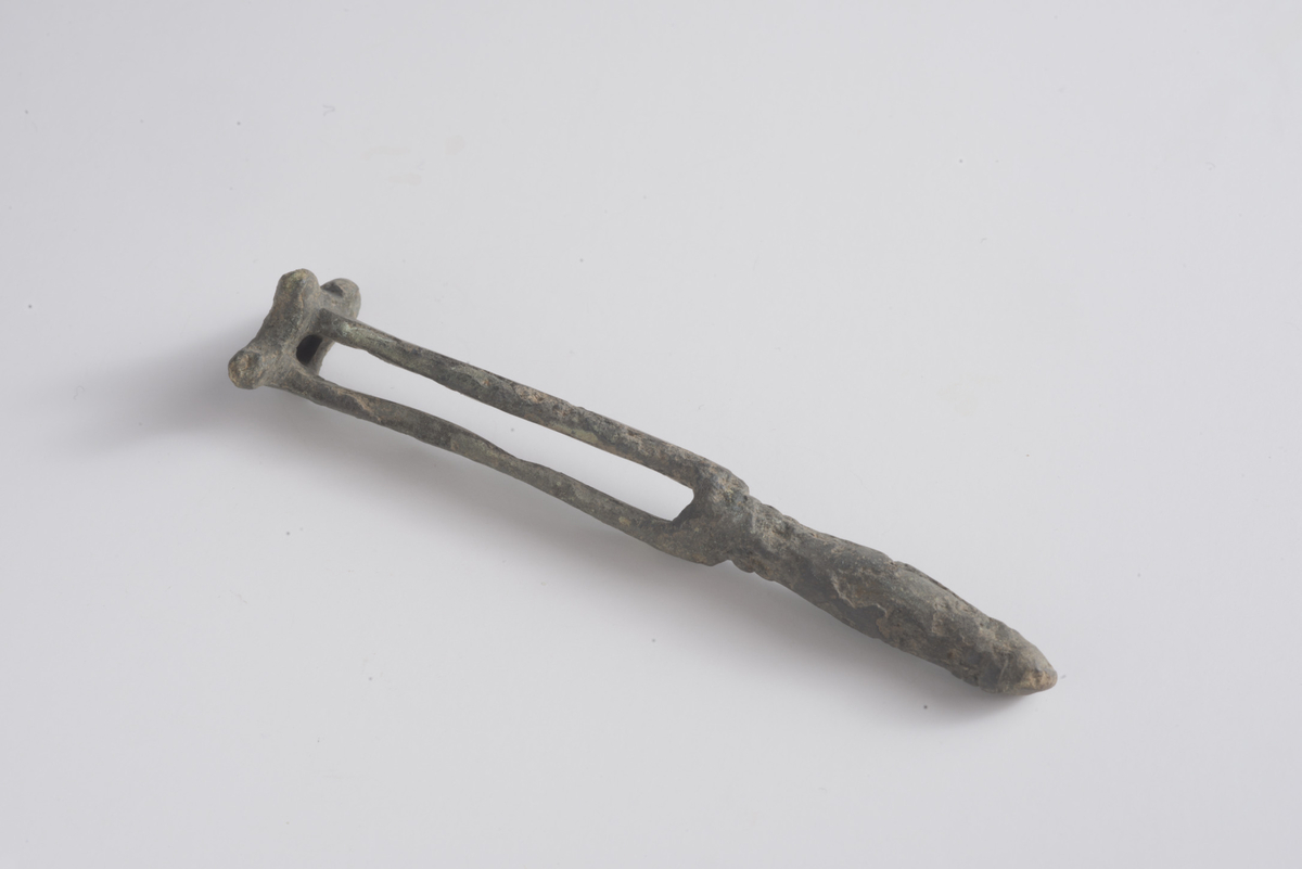 Nøkkel, boltlåsnøkkel av kobber lik R456. Håndtak (L: 33 mm) dekorert med en svakt markert rundløpende vulst/strek ved avslutning av hode og ved overgang til skaft (L: 46 mm). Skjegget har tre knopper satt i en trekant. Overflaten på nøkkelen er delvis korrodert.