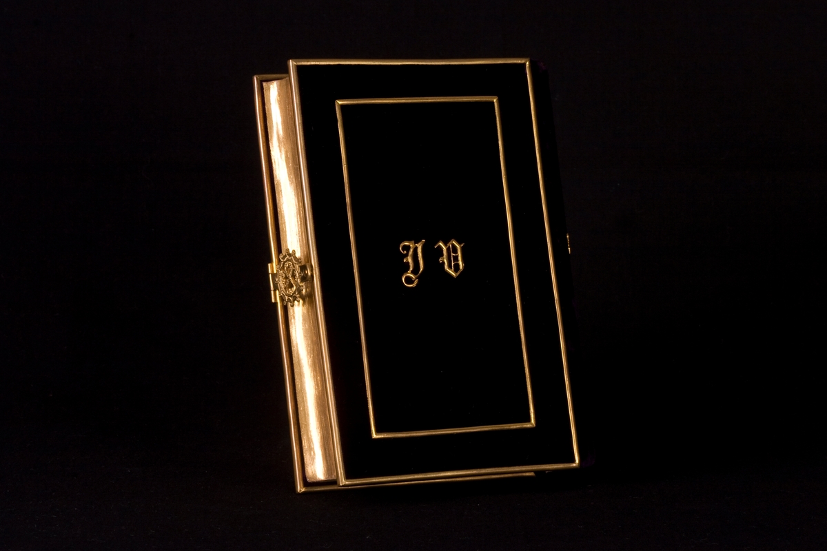 Bönbok (siddur) med sammetsomslag i djupt lila, med guldfärgat lås på sidan. Framsidan av boken dekorerad med initialerna A E i guldfärg. Boken är skriven på franska och hebreiska, och är tryckt 1869.