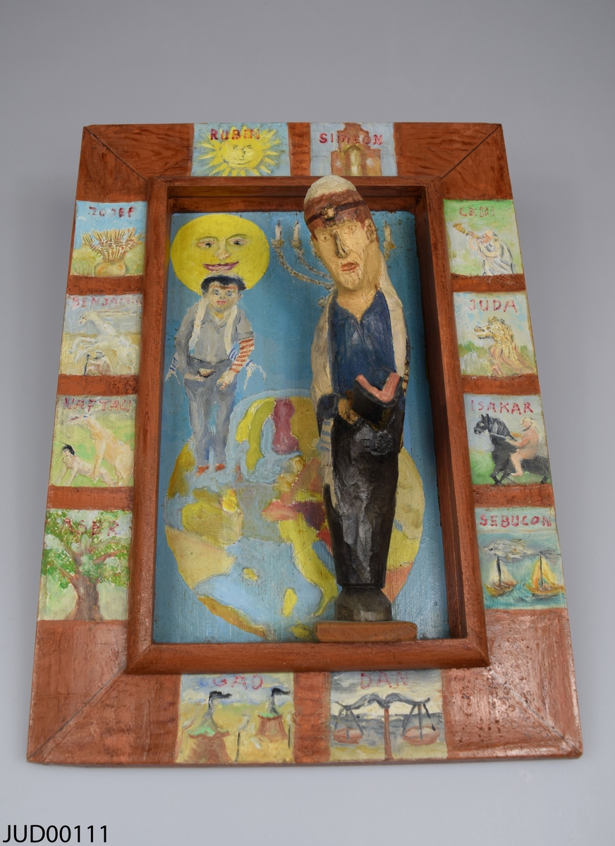 Tavla, bemålat trä med en bemålad ram. Stor tredimensionell bemålad träfigur i mitten av tavlan föreställande judisk man med tefillin och tallit. Bilderna som är målade runt om på ramen föreställer judiska stamfäder. På baksidan finns signaturen ”Albert Mankovitz -99”.