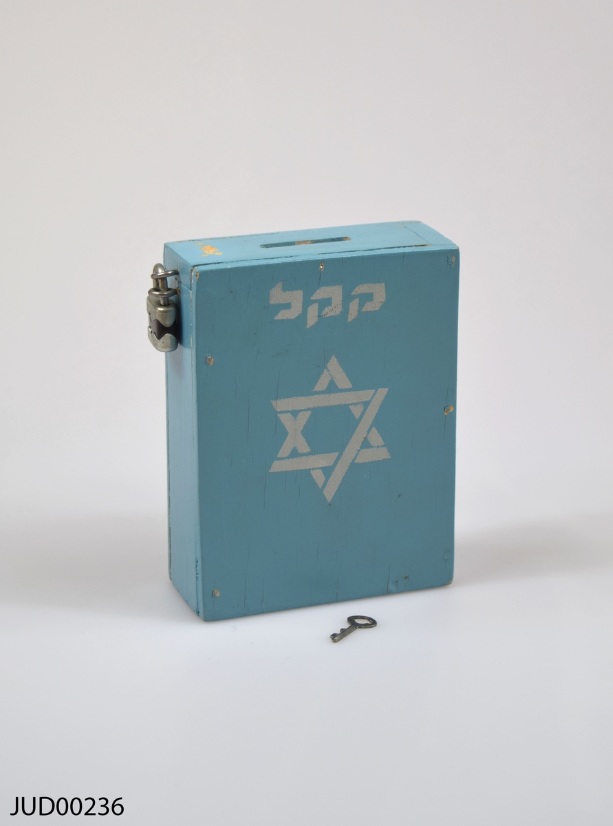 Insamlingsbössa, tillverkad av trä och målad med ljusblå färg. Dekorerad med en vit davidsstjärna samt vit hebreisk text.