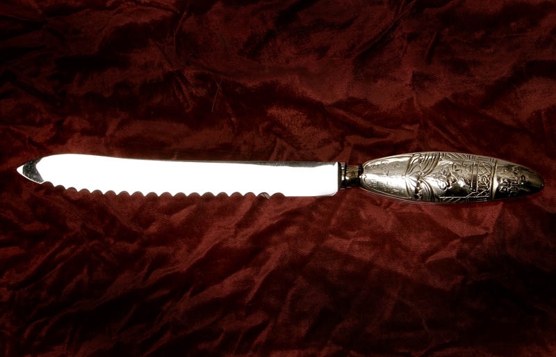 Challakniv tillverkad av silver, med flätad dekor på handtagets ena sida och shabbatmotiv på andra sidan.