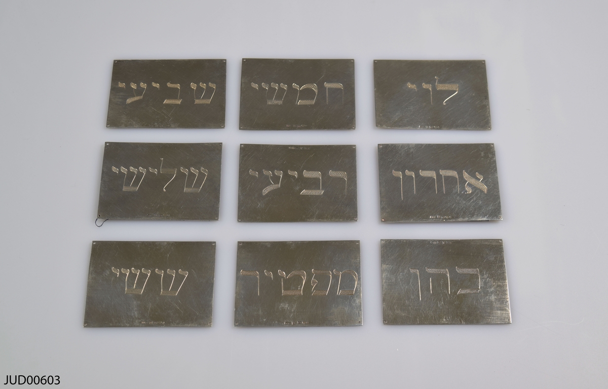 Nio brickor av silver med hebreisk text. För kallelse till toraläsning i synagogan.
