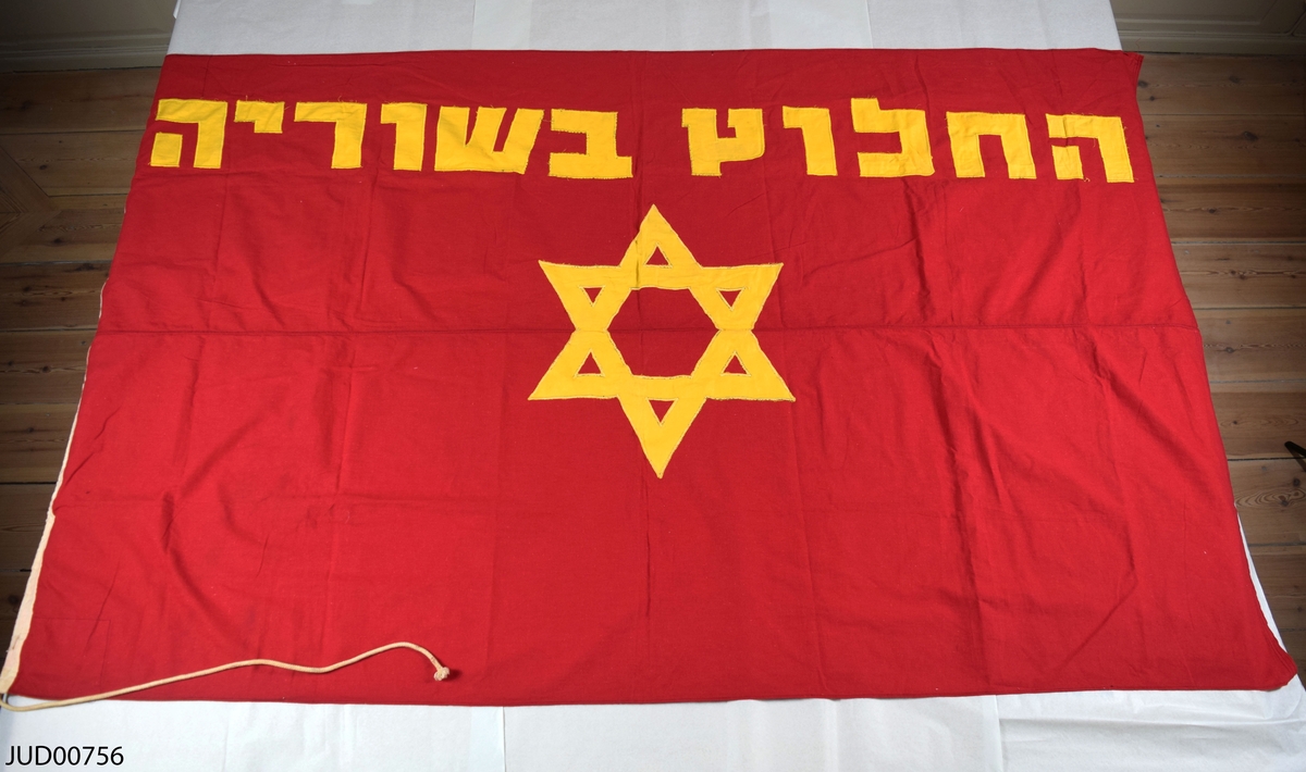 Röd flagga med hebreisk text i gult samt davidsstjärna