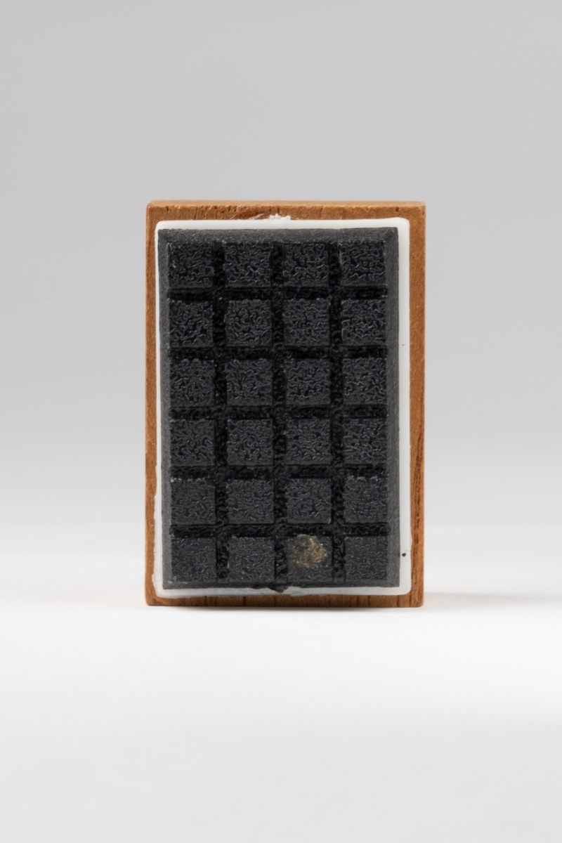 Grammofonhögtalare till dockskåp, av brunt trä med svart plast framtill, som är rutad, omgiven av smal kant av vit plast.